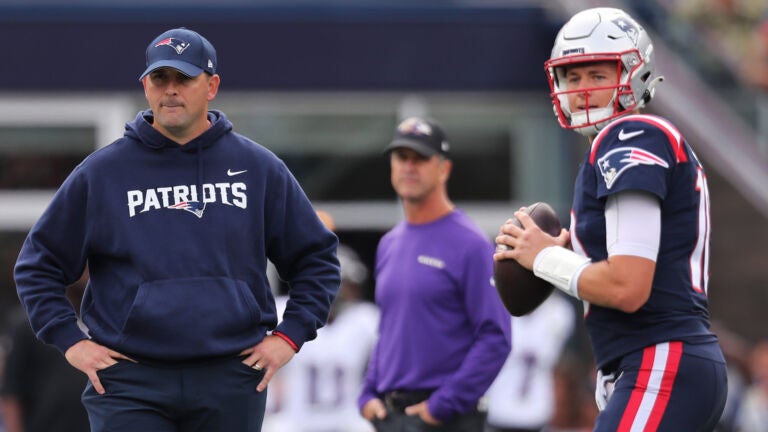 Both Patriots quarterback coach Joe Judge (left) and Ravens head coach John Harbaugh (backround center) were watching as New England quarterback Mac Jones (10) was warming up before the start of the game.