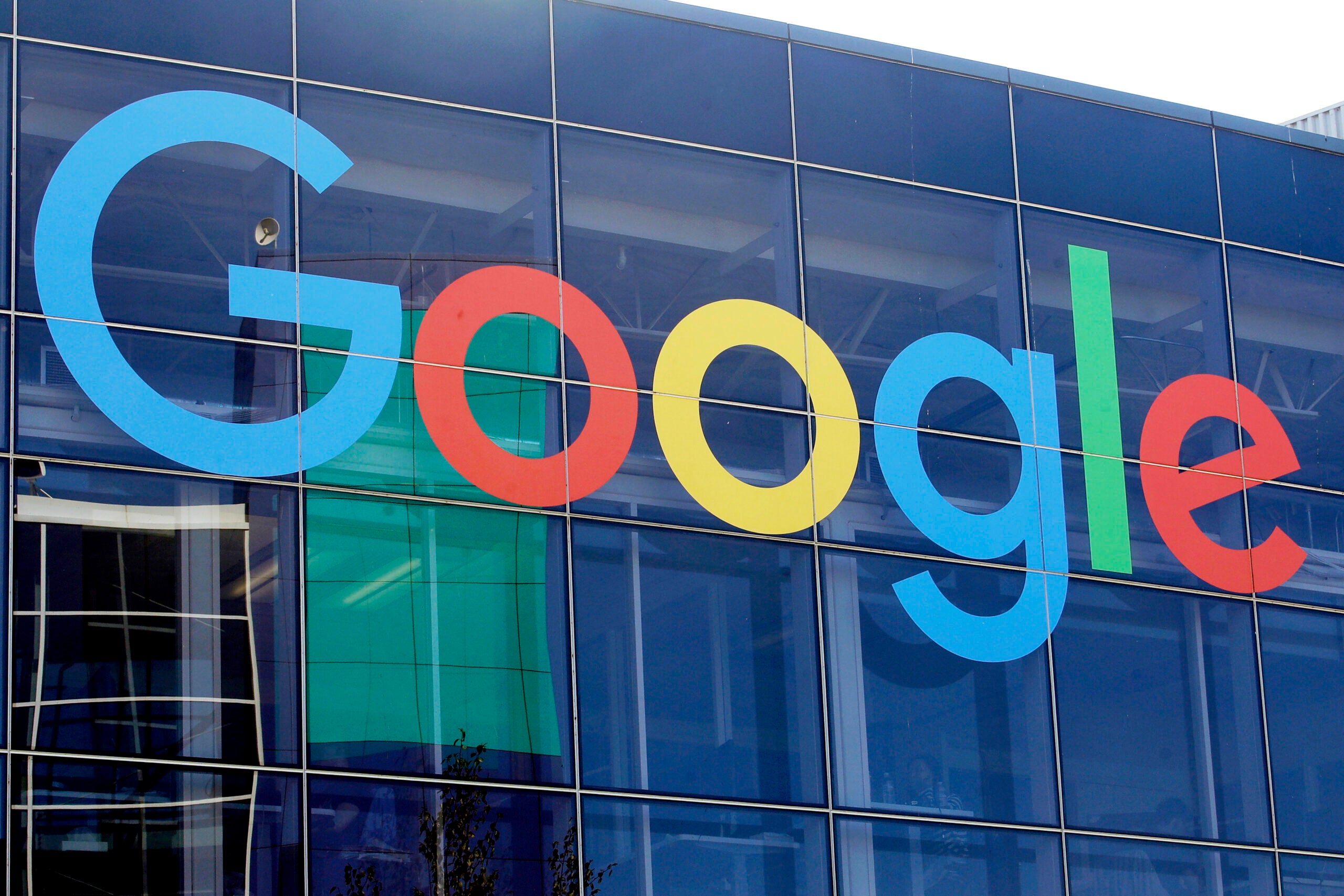 alt = A sign is shown on a Google building at their campus in Mountain View, Calif. featuring the classic blue, red, yellow, and green logo.