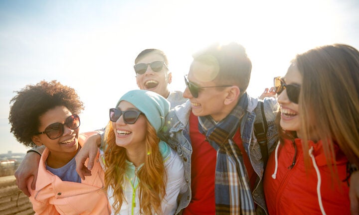 alt = group of smiling teens wearing sunglasses with their arms around one another