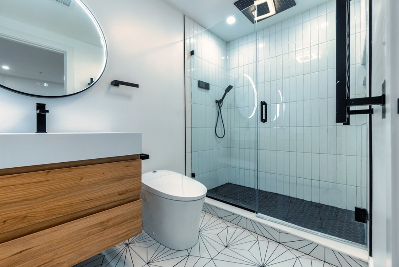 The bathroom has white walls, a white-tiled shower and patterned tile floors.