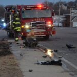 alt = A Hingham firetruck and firefighter at the scene of a crash on on Lincoln Street (Route 3A) at the intersection of Shipyard Drive Sunday. Debris from the crash is seen on the road in front of the truck.