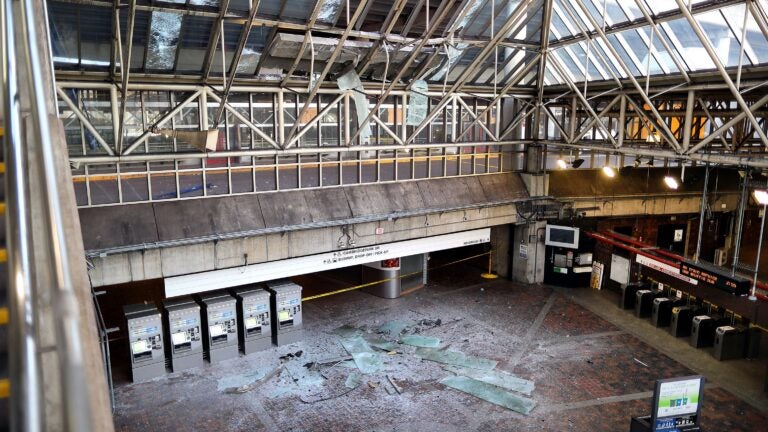 A car on the top floor of the Alewife Station parking garage Saturday plowed into a concrete barrier, which fell onto the glass-paneled atrium of the lobby, smashing close to a dozen windows. Debris lined the floor of the lobby.