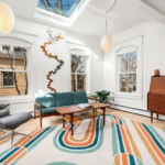A living room with white walls, double-hung windows, maple floors and a skylight.