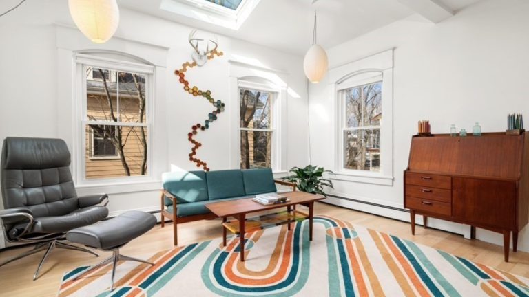 A living room with white walls, double-hung windows, maple floors and a skylight.