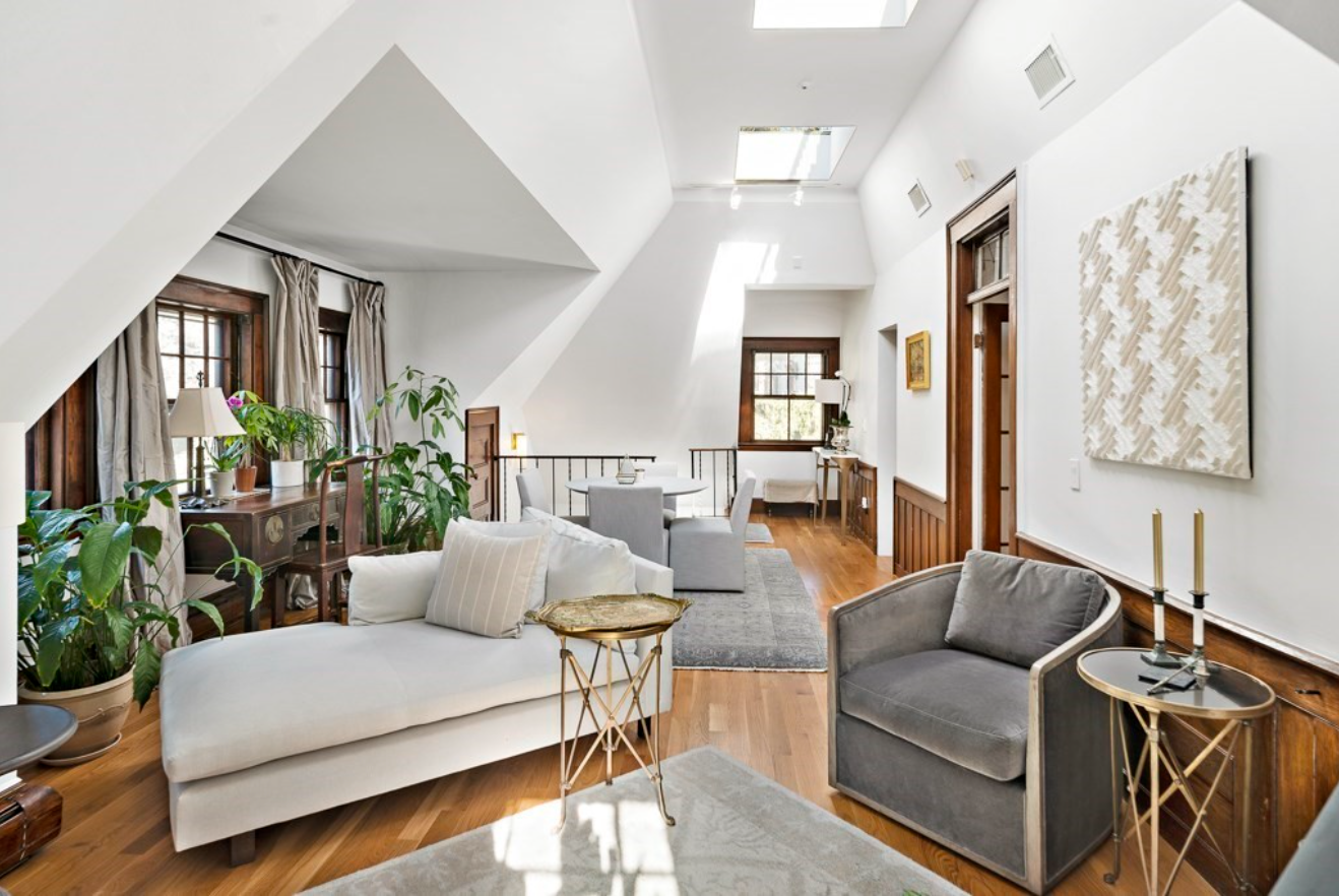 The living room has vaulted ceilings and white walls with skylights.