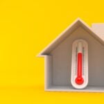 Thermometer inside house cross-section isolated on orange background to show a hot home. 3d illustration