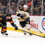 Vancouver Canucks' Tyler Myers (57) tries to check Boston Bruins' Matt Grzelcyk during the first period of an NHL hockey game, Saturday, Feb. 25, 2023 in Vancouver, British Columbia.