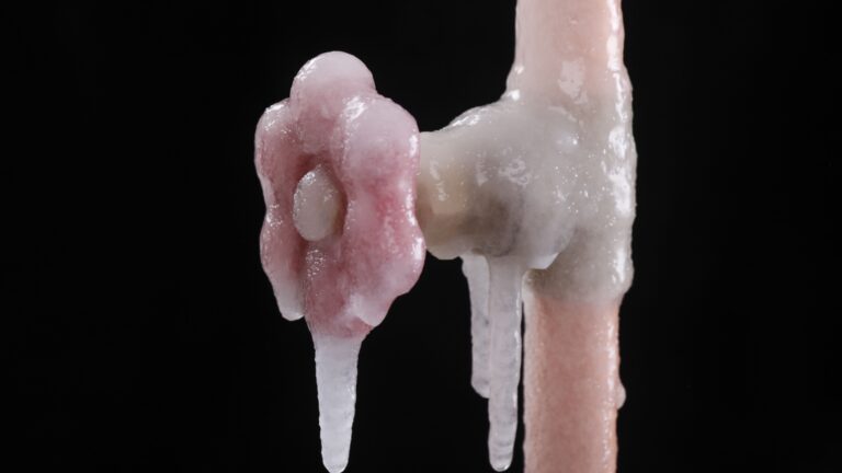 A frozen pipe with ice hanging off of it.