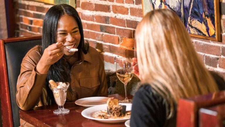 Two women eat together at Grotto in Boston