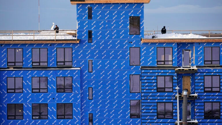 multi-story building under construction clad in blueboard