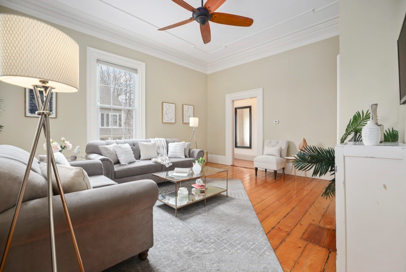 The living room has hardwood floors, dentil molding and beige walls with single-hung windows.