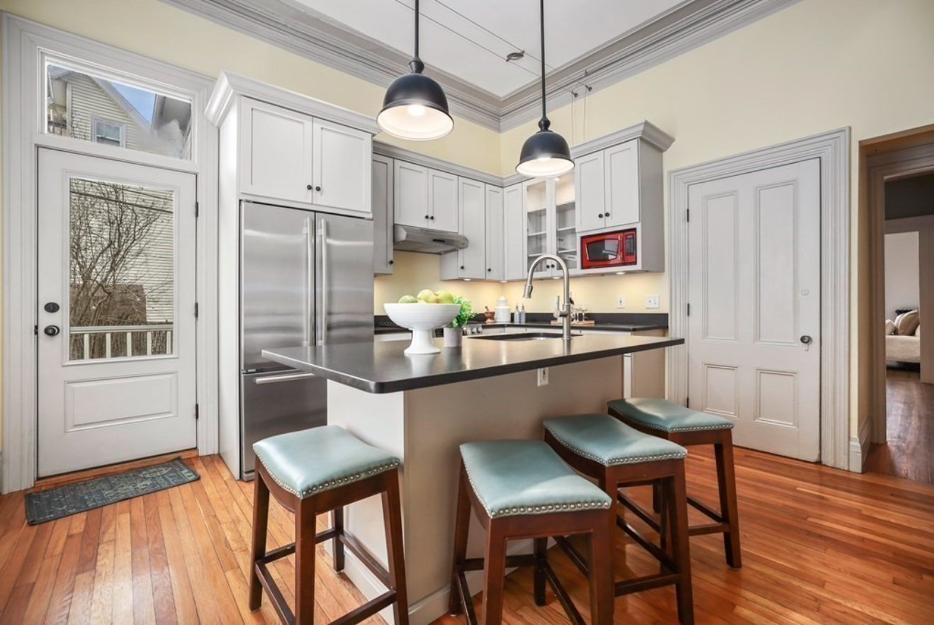 The kitchen has Shaker-style cabinets, hardwood floors, crown molding and an island with seating for four.