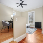 The bedroom has single-hung windows, hardwood floors, beige walls and an office nook.