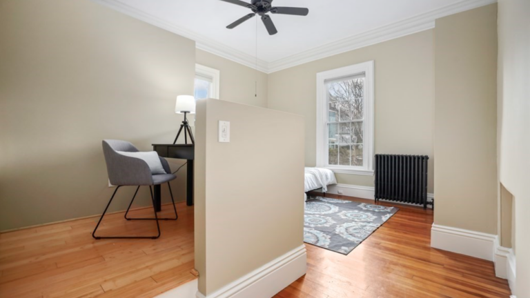 The bedroom has single-hung windows, hardwood floors, beige walls and an office nook.
