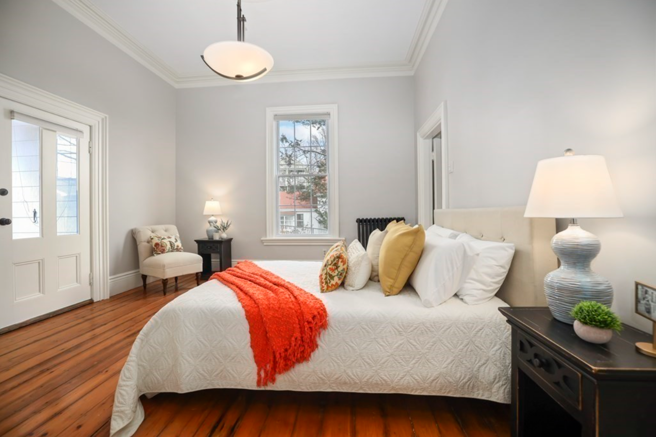The second bedroom has light gray walls, hardwood floors, pendant lighting and single-hung windows.