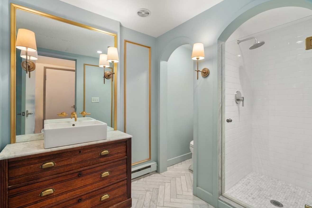 The bathroom has herringbone tile floors and light blue walls with a single vanity and standalone bathtub.