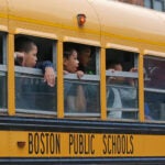 Elementary school children look out the windows of a Boston Public Schools bus.