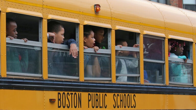 Elementary school children look out the windows of a Boston Public Schools bus.