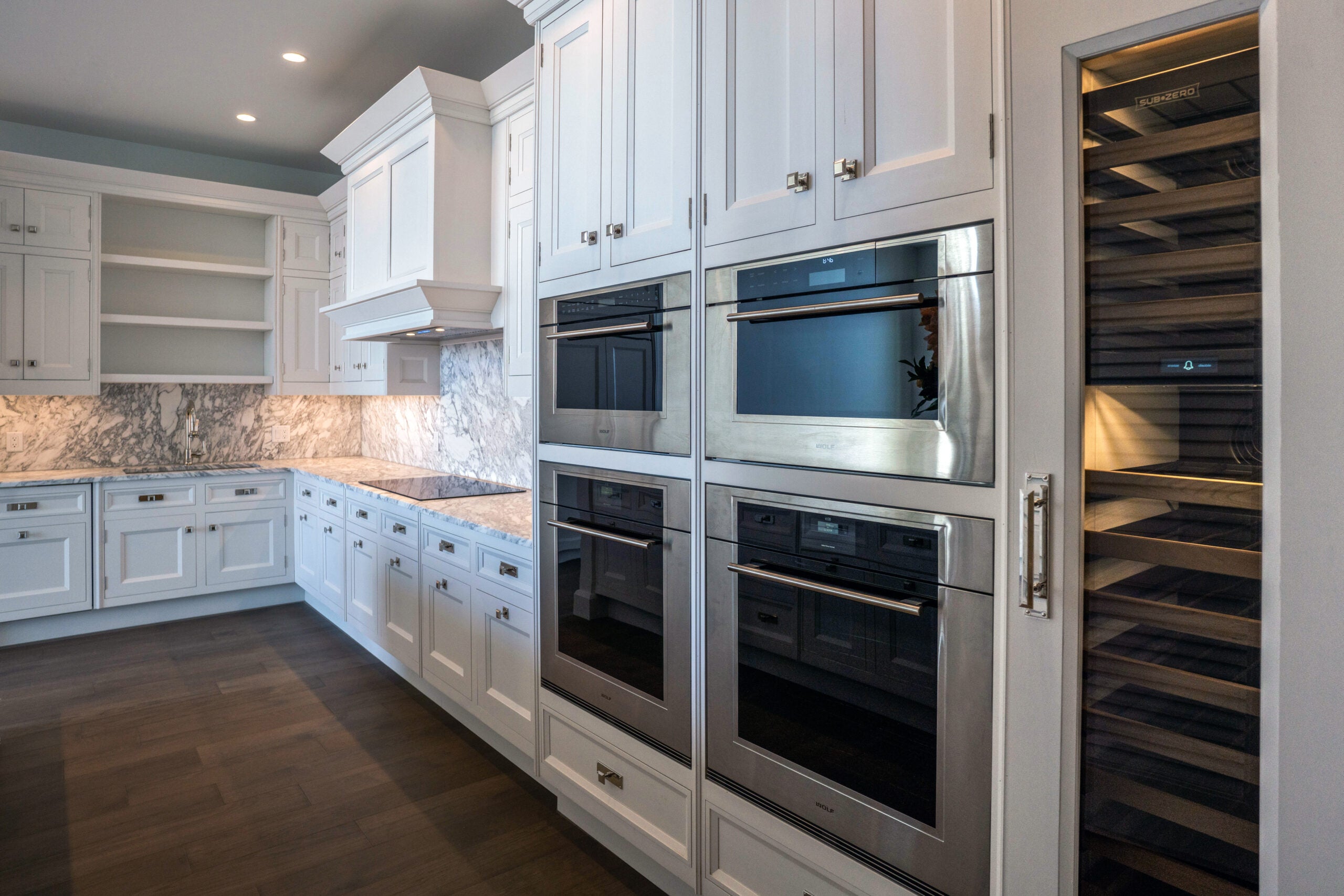 A close-up of stainless steel appliances set among white kitchen cabinets.