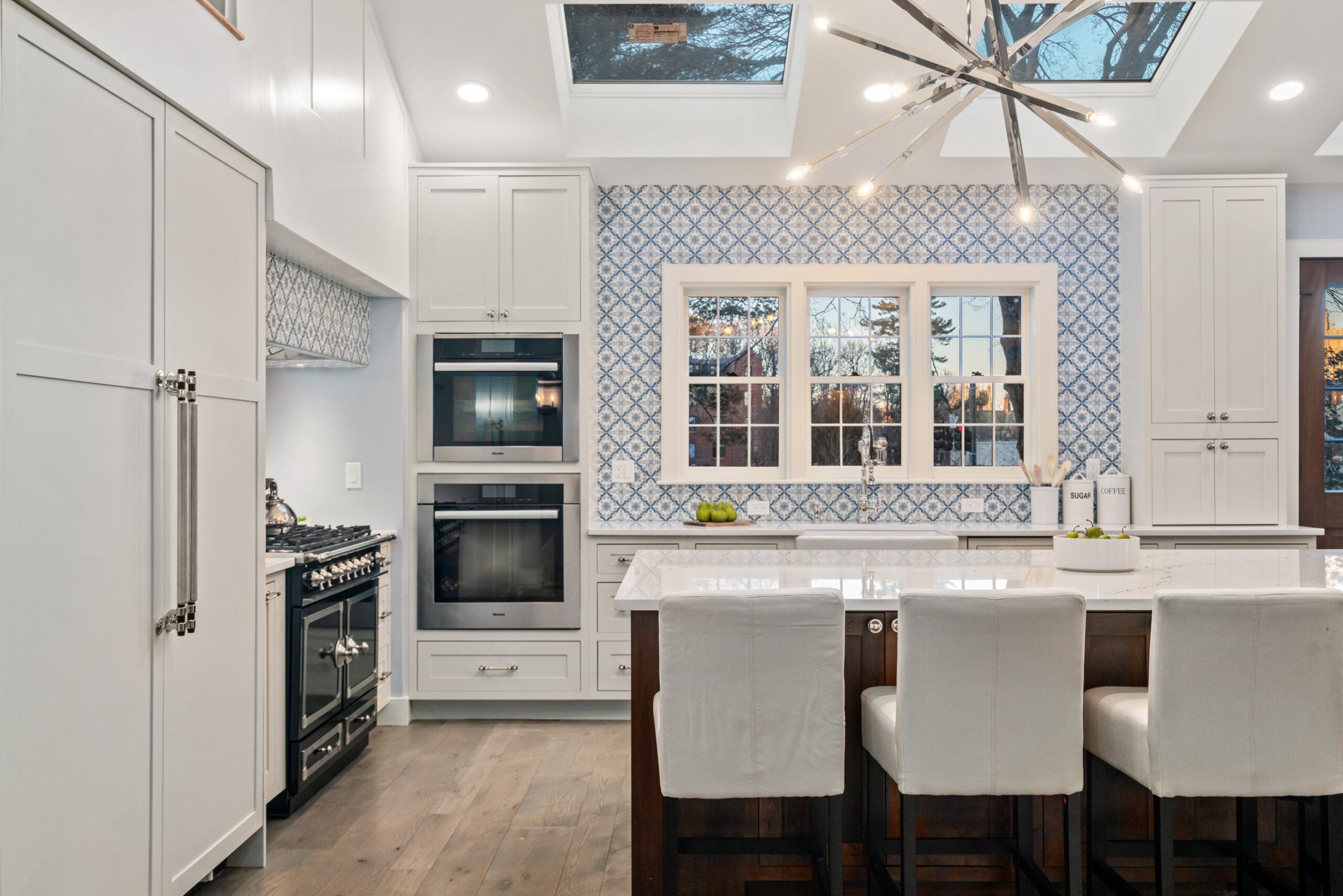 The kitchen has skylights, a sputnik chandelier, and white Shaker-Style cabinets.