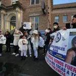 A group of people gather outside the East Boston police station holding signs bearing missing woman Reina Morales Rojas' face and calling for information in her disappearance.