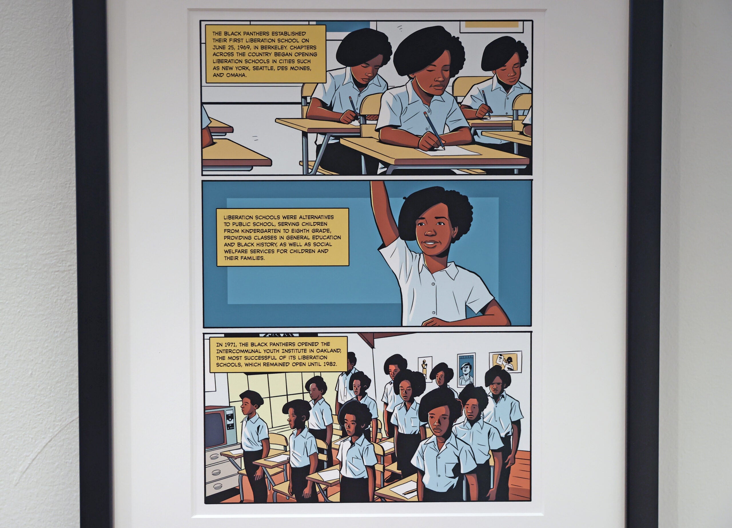 A girl raises her hand in a page from Marcus Kwame Anderson's "Liberation Schools," 2020., hanging in the Boston University Stone Gallery