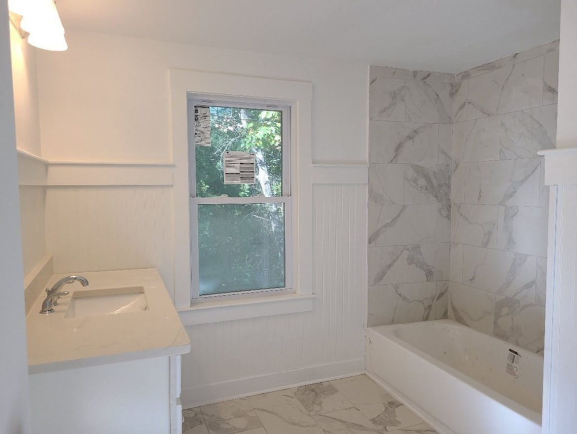 The bathroom has a walk-in shower and single vanity with a single-hung window.