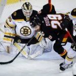 Boston Bruins defenseman Dmitry Orlov, right, checks Calgary Flames forward Dillon Dube, center, in front of goalie Linus Ullmark during the third period.