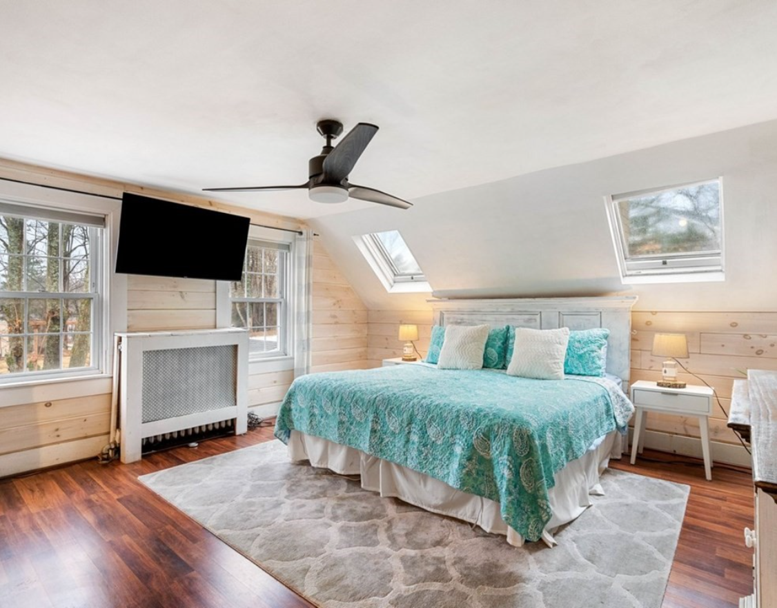 The primary bedroom has two skylights, hardwood floors, and exposed wood walls.