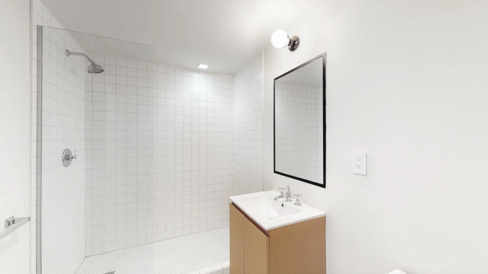 The bathroom has a single vanity with sconce lighting and a combination shower-bathtub.