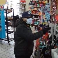 A man wearing a Yankees cap holds a gun during a robbery at a Hingham convenience store.