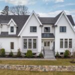 A white single-family home with no shutters, a dormer, and sharp roof lines is used as an example of open houses being held this weekend.