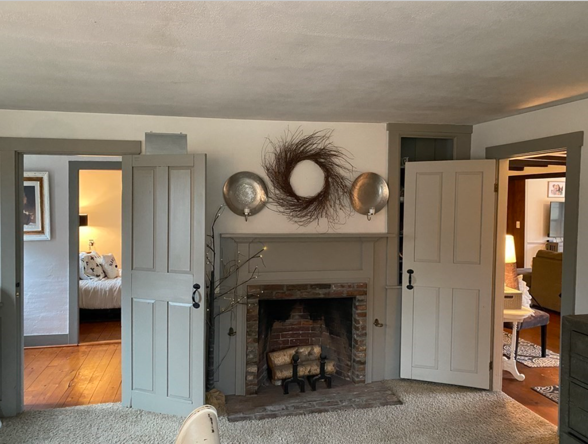 The living room has carpeted floors, white walls and a fireplace.
