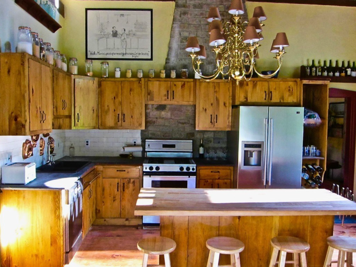 The kitchen has wooden cabinets, an island with seating for four, and stainless steel appliances.