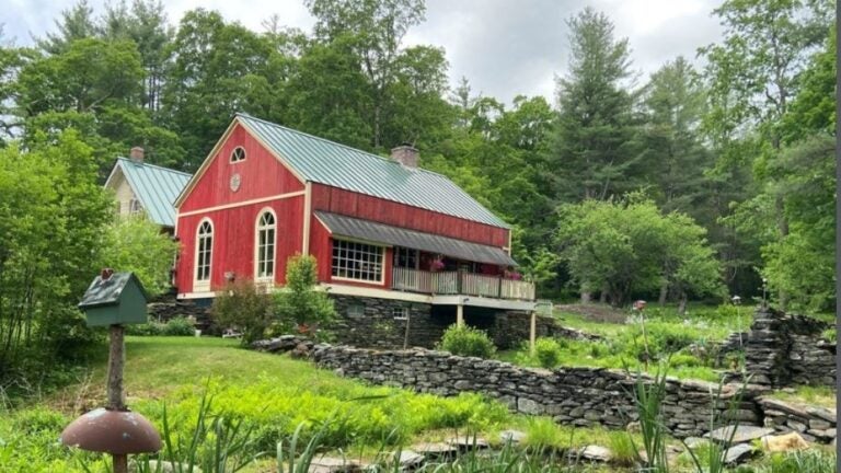 An old home on the market with a red barn and a pond.