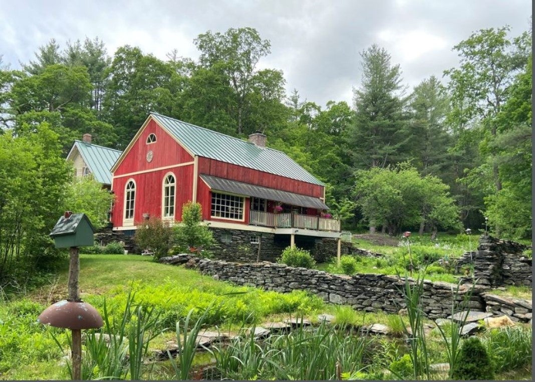 An old home on the market with a red barn and a pond.