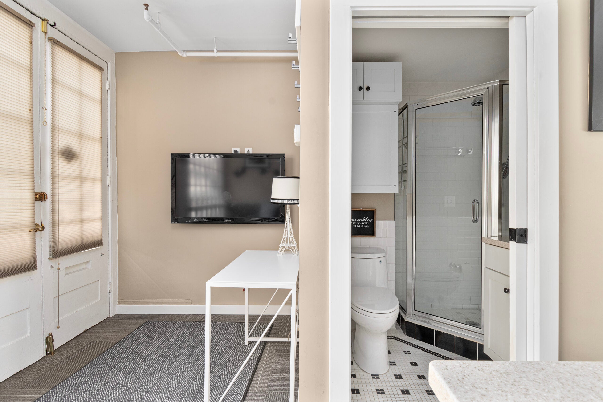 The bathroom offers a semi-frameless shower and above-toilet cabinetry for storage.
