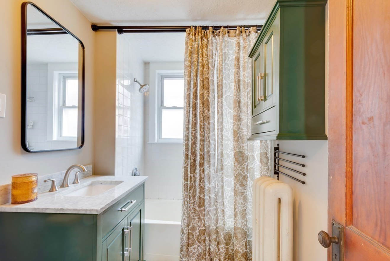 The bathroom has olive green cabinets and a combination shower-bathtub.