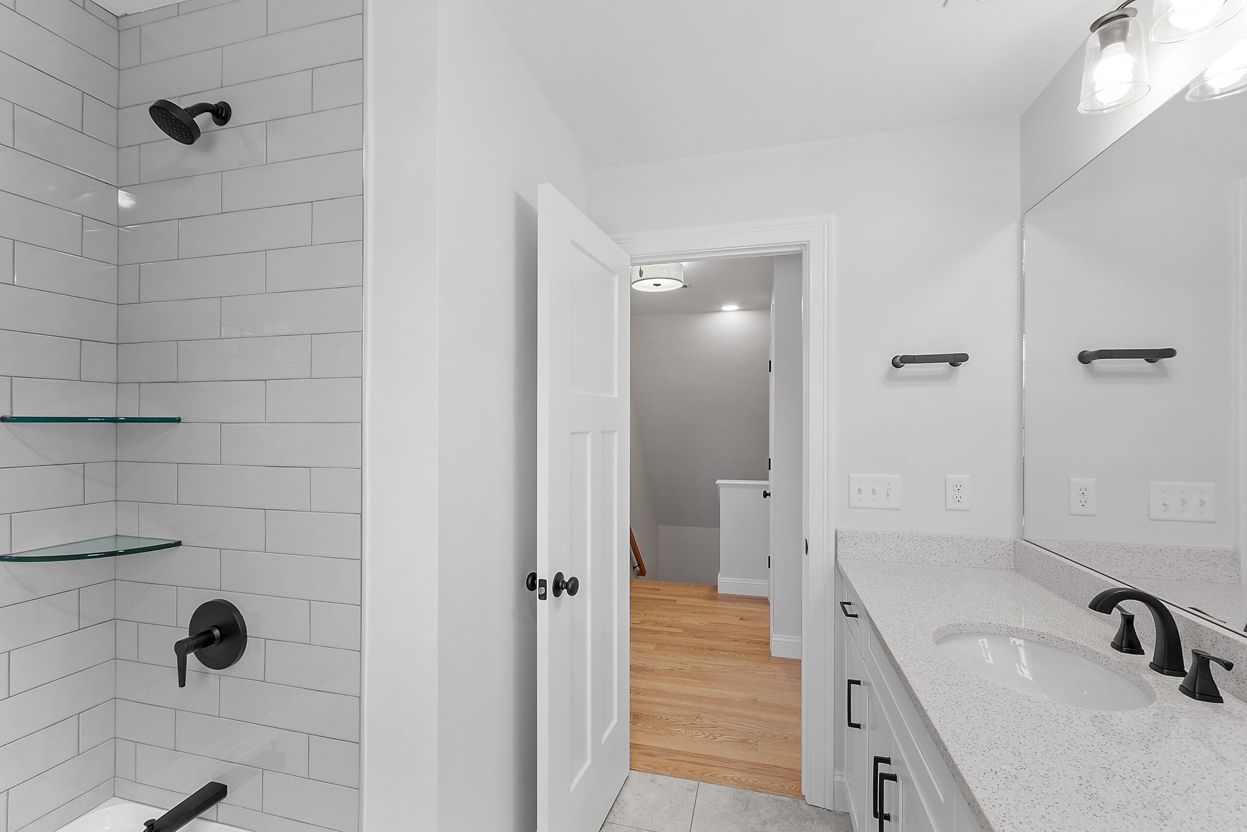 a bathroom with white cabinetry, white walls, white countertops, and a tub/shower combination with a white subway tile surround. The fixtures and handles are black.