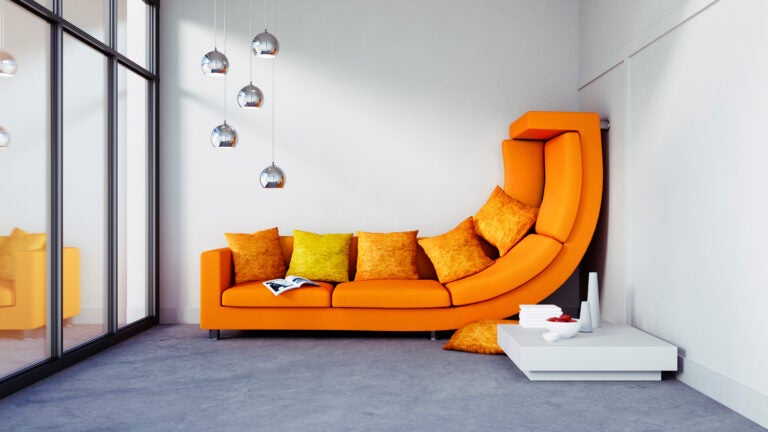 An orange sofa is squished up a wall to illustrate apartment size.