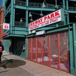 A man walks outside Fenway Park.