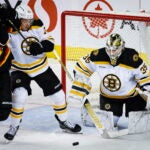 Boston Bruins defenseman Charlie McAvoy, center, keeps Calgary Flames forward Mikael Backlund, left, away from the puck as goalie Linus Ullmark watches during the second period of an NHL hockey game Tuesday, Feb. 28, 2023, in Calgary, Alberta.
