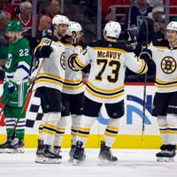 Boston Bruins Pavel Zacha, Charlie McAvoy (73) and Tyler Bertuzzi celebrate a goal with David Pastrnak, second left, as Carolina Hurricanes' Brett Pesce (22) skates nearby during the second period of an NHL hockey game in Raleigh, N.C., Sunday, March 26, 2023.