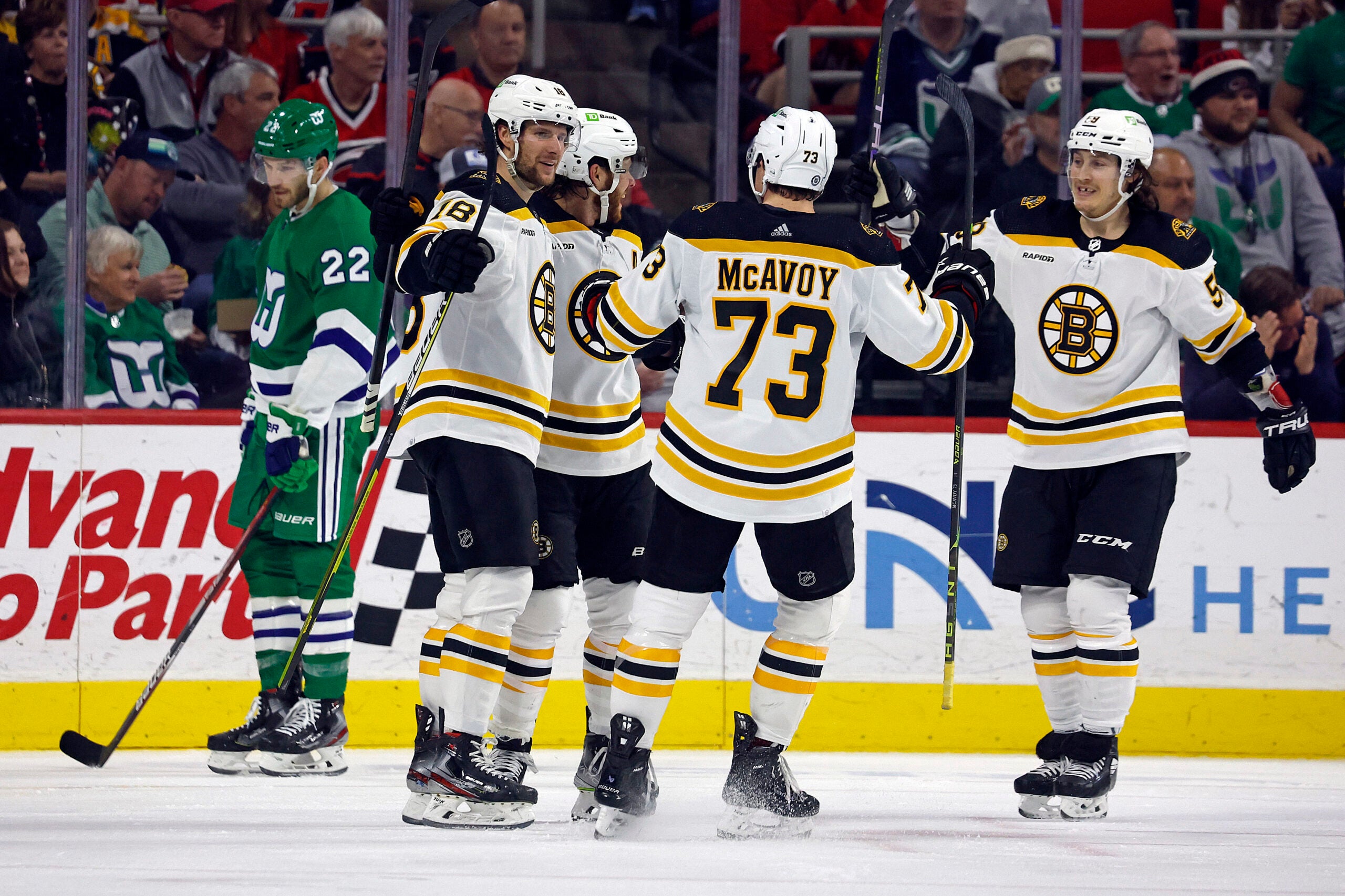 Boston Bruins Pavel Zacha, Charlie McAvoy (73) and Tyler Bertuzzi celebrate a goal with David Pastrnak, second left, as Carolina Hurricanes' Brett Pesce (22) skates nearby during the second period of an NHL hockey game in Raleigh, N.C., Sunday, March 26, 2023.