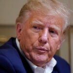 Former President Donald Trump listens as he speaks with reporters