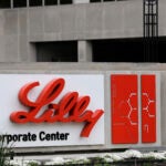 The Eli Lilly & Co. corporate headquarters in Indianapolis. Concrete building with red and black lettering on a white sign.