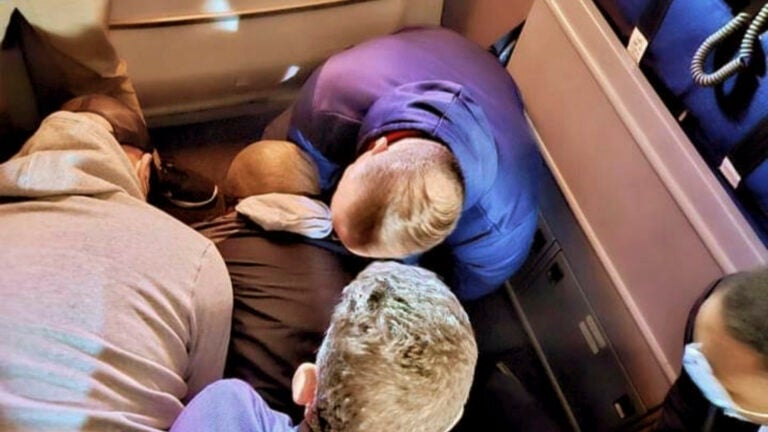 Several passengers and flight attendants are shown on the floor in an airplane galley, holding passenger Francisco Severo Torres down after he allegedly attempted to stab a flight attendant.
