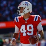 New England Patriots long snapper Joe Cardona (49) holds a ball during the first half of an NFL football game against the Detroit Lions, Sunday, Oct. 9, 2022, in Foxborough, Mass.