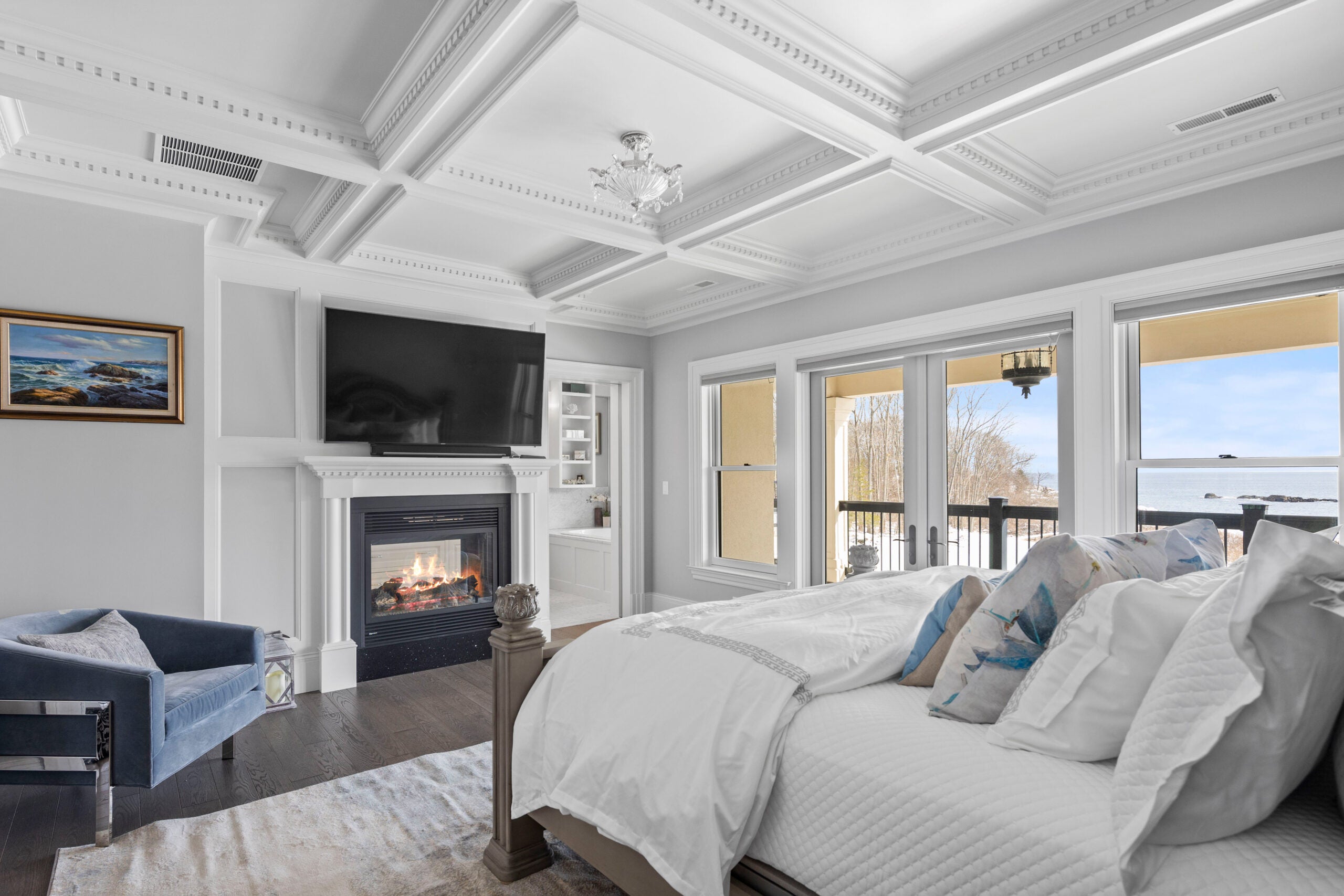 The primary bedroom includes coffered ceilings and a gas fireplace, as well as a sliding glass door that leads to a private deck.