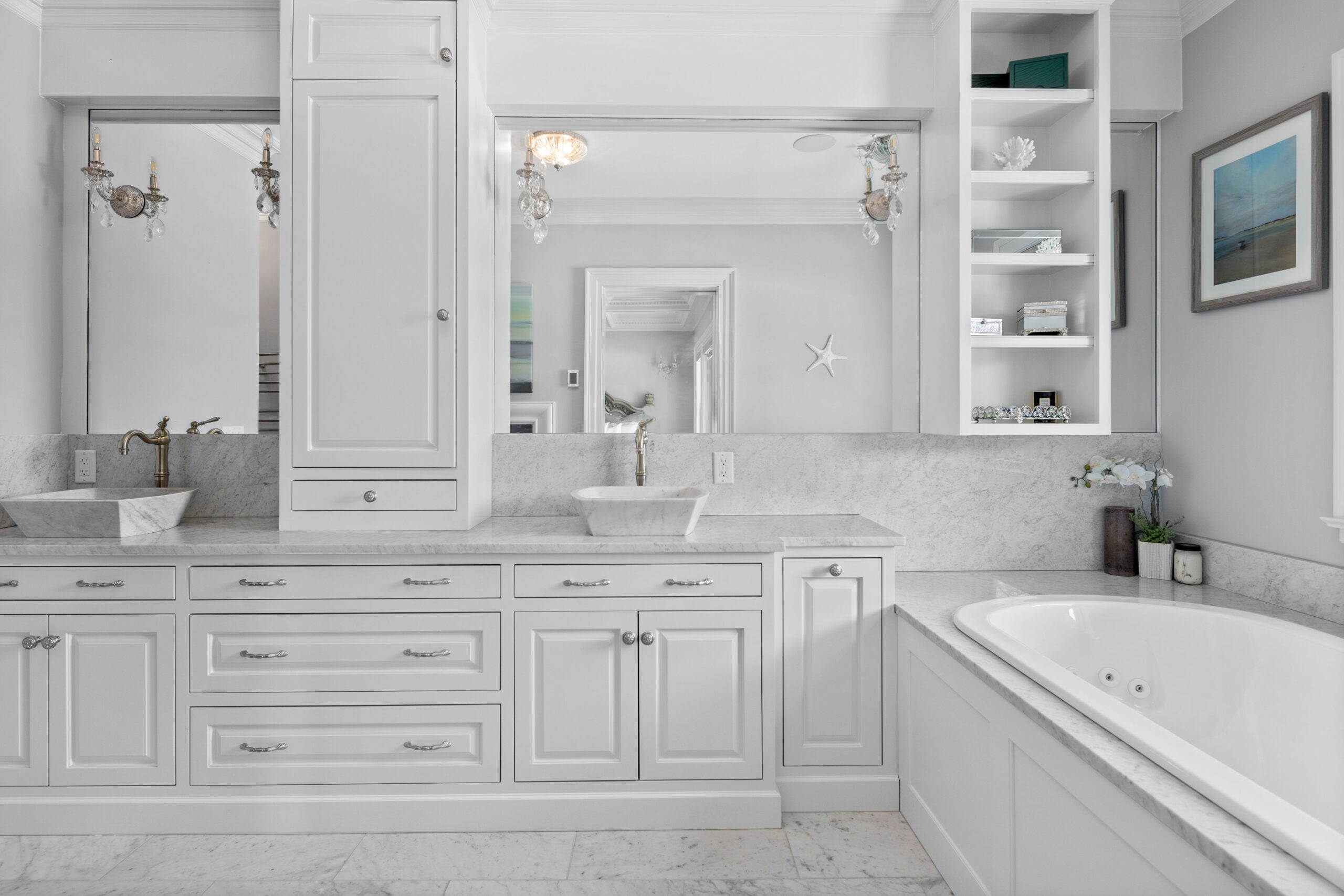 The primary bathroom has fresh white cabinets and walls, a double vanity, and soaking tub with ocean views.